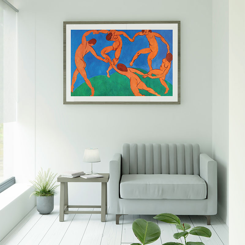 Quadro Decorativo A Dança Matisse com moldura de madeira e passe-partout branco, decorando sala clara com sofá cinza e mesa lateral.