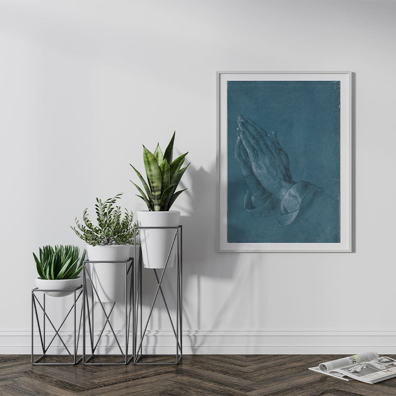 Quadro Decorativo Mão que Oram Pendurado ao Lado de Planta Verde.