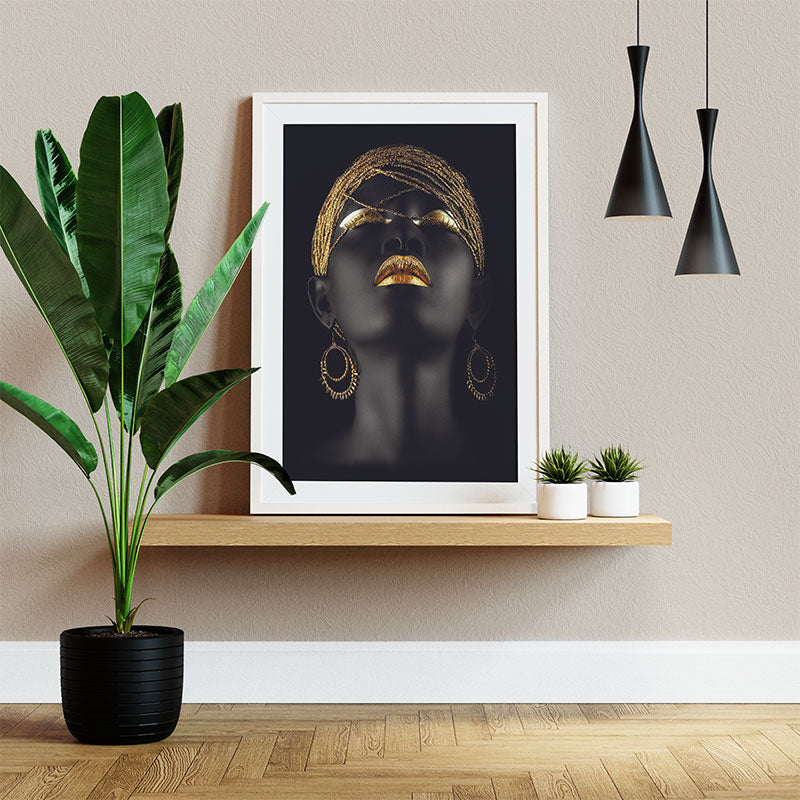 Quadro Decorativo Negra Dourada Pendurado ao Lado de Planta Verde.